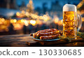 A large beer mug filled with golden beer sits next to grilled sausages on a wooden table. The background features festive lights, typical of Oktoberfest in Bavaria, Germany. 130330685