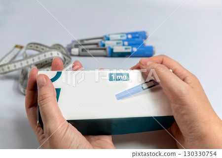 Hands holding Ozempic Insulin injection pen for diabetics and weight loss. Medical equipment for diabetes parients. Hands holding Ozempic Insulin injection pen for diabetics and weight loss. Medical equipment for diabetes parients. 130330754
