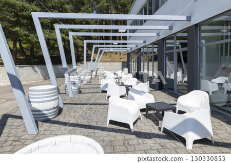 Outdoor seating area with white chairs and wine barrels decorating the space Outdoor seating area with white chairs and wine barrels decorating the space 130330853