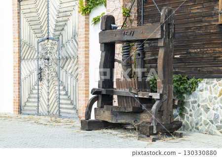 Old wooden wine press standing in front of a wooden gate in Dolany, Slovakia Old wooden wine press standing in front of a wooden gate in Dolany, Slovakia 130330880