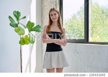 Portrait of smiling young woman looking at camera with crossed arms in home 130331045