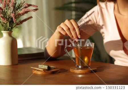 Woman hand stirring tea at home at sunset 130331123