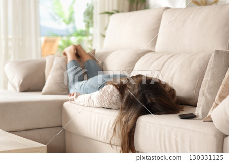 Tired woman lying on a couch resting at home Tired woman lying on a couch resting at home 130331125