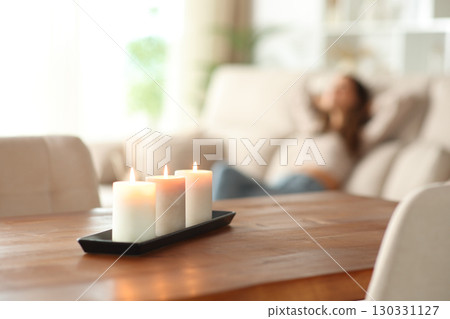 Aromatic candles and woman relaxing in the background 130331127