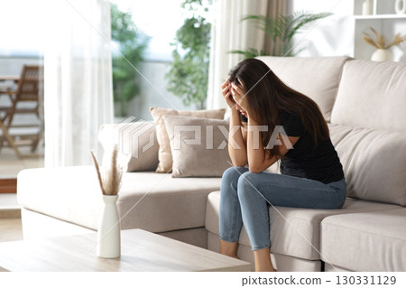Sad woman complaining alone in a house interior 130331129