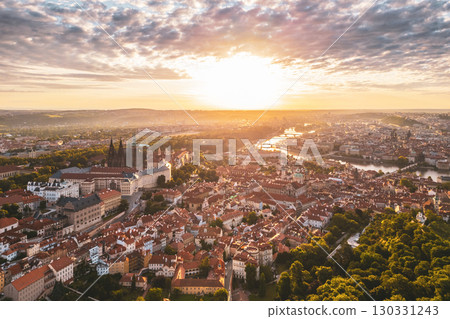 Sunrise casts a warm glow over Prague Castle and the vibrant rooftops of the city. The picturesque landscape, with rivers and greenery, captures a serene morning atmosphere in Praha. Sunrise casts a warm glow over Prague Castle and the vibrant rooftops of the city. The picturesque landscape, with rivers and greenery, captures a serene morning atmosphere in Praha. 130331243