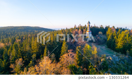 Stepanka Lookout Tower rises majestically in the Jizera Mountains during a serene spring morning. The surrounding forest reveals fresh greenery, inviting nature lovers to explore the area. 130331264