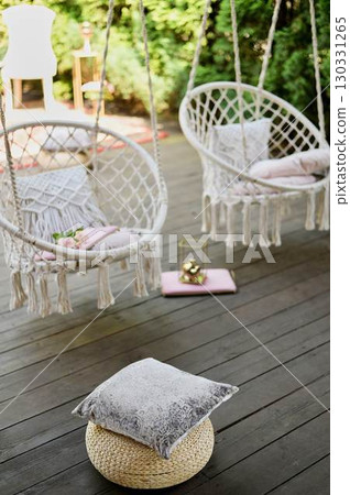 The swing is light wicker with a soft pillow in the style of macrome. Boho style, garden design. 130331265