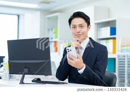 Middle-aged businessman using a smartphone in the office Middle-aged businessman using a smartphone in the office 130331426