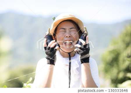 Woman harvesting vegetables in the field. Image of a farmer or agricultural worker. Close-up of a smiling woman looking at the camera. Woman harvesting vegetables in the field. Image of a farmer or agricultural worker. Close-up of a smiling woman looking at the camera. 130331646
