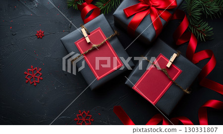 Black christmas gift boxes with red ribbons and blank tags on dark background with festive decor 130331807