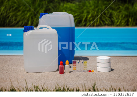Poolside arrangement with large chemical containers, test kit, dropper bottles, and chlorine tablets used for pool maintenance and water quality control. Poolside arrangement with large chemical containers, test kit, dropper bottles, and chlorine tablets used for pool maintenance and water quality control. 130332637