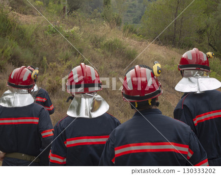 group of four firefighters observing the smoking mountain 130333202
