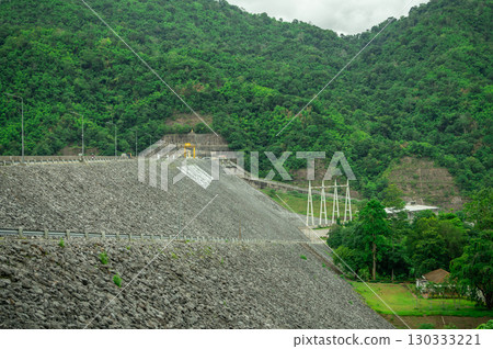 Concrete reinforced dam crest construction with rock fill embankment showcasing modern hydroelectric infrastructure engineering for sustainable renewable energy power generation facility. 130333221