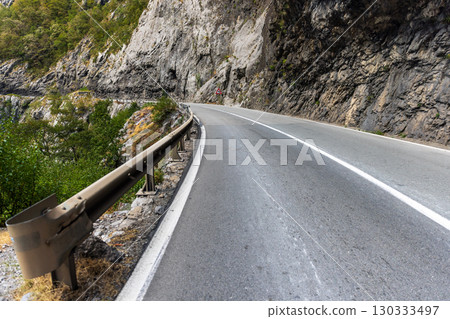 Scenic view of a sharp mountain road turn surrounded by rocky cliffs Scenic view of a sharp mountain road turn surrounded by rocky cliffs 130333497