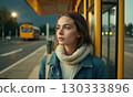 Young woman is standing at the city bus stop 130333896