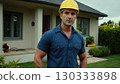 Man in yellow helmet standing in front of the house. He's wearing uniform and he's construction 130333898