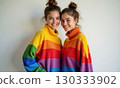 Two women in bright rainbow striped sweaters smile at the camera. The concept of happiness and 130333902