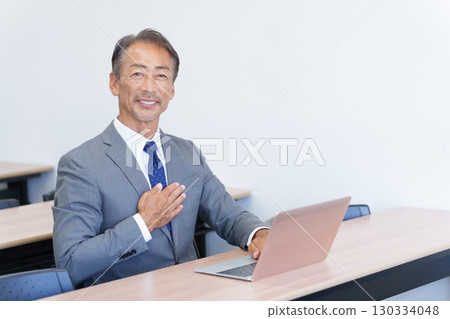 Senior businessman using a computer and putting his hand on his chest 130334048