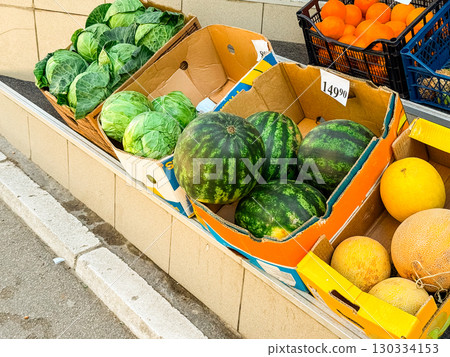Fresh fruits and vegetables including watermelon, cabbage, melon and orange displayed in cardboard boxes. Market trade, agriculture produce and healthy food supply for commerce and seasonal nutrition. 130334153