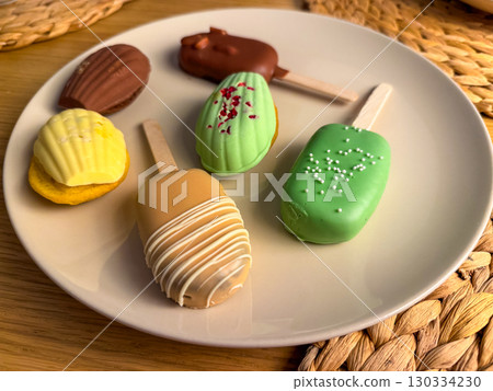 Assorted desserts on a plate, colorful cakes and popsicles. Modern food styling. Concept of variety, sweets, aesthetics of food. 130334230