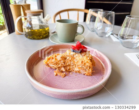 Slice of layered cake with berries served with tea in cafe. Dessert and beverage symbolizing sweet indulgence, lifestyle dining and culinary culture. 130334299