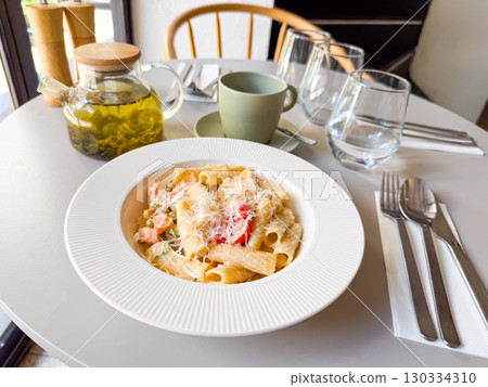 Pasta dish with vegetables and cheese served with herbal tea in cafe. Dining moment symbolizing nutrition, lifestyle and gourmet cuisine culture. 130334310