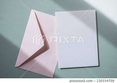 Empty white blank greeting or invitation card with pink envelope on blue background. Mock up presentation. 130334709