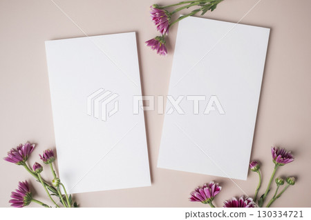 White blank greeting or invitation card with purple flower decoration on beige background. White blank greeting or invitation card with purple flower decoration on beige background. 130334721