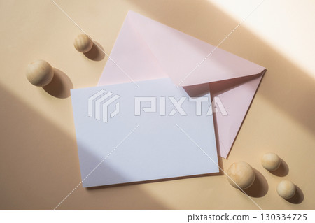 Empty white blank greeting or invitation card with pink envelope on beige background. Mock up presentation. 130334725