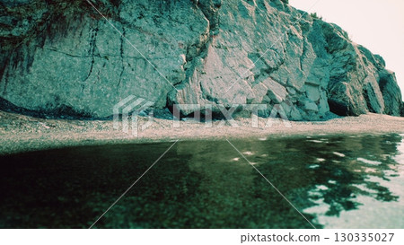 A massive rock sits atop a beautiful South African beach with the ocean in the background. 130335027