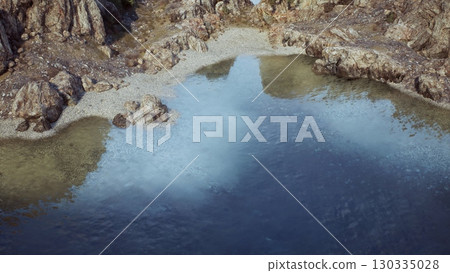An aerial perspective capturing the stunning beauty of a body of water surrounded by rocks along the captivating rocky coast of Australia. 130335028