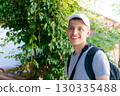 Young man wearing a white hat and a grey shirt is smiling 130335488