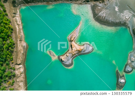 The effects of pollution on a natural habitat, featuring damaged terrain and pools of toxic water surrounded by lush hills. The effects of pollution on a natural habitat, featuring damaged terrain and pools of toxic water surrounded by lush hills. 130335579