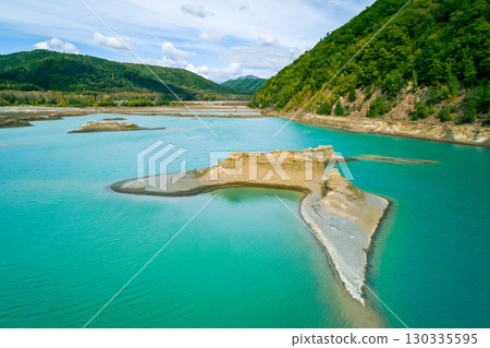 The effects of pollution on a natural habitat, featuring damaged terrain and pools of toxic water surrounded by lush hills. 130335595