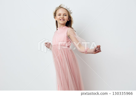 A joyful young girl in a pink dress with a delicate tulle skirt, smiling against a minimalist white background, showcasing happiness and childhood joy A joyful young girl in a pink dress with a delicate tulle skirt, smiling against a minimalist white background, showcasing happiness and childhood joy 130335966