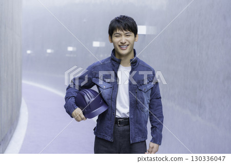 一名身穿牛仔工作服、手持頭盔的年輕男子的畫像 130336047