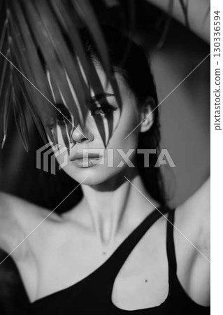 Monochrome portrait of a woman with palm leaf on her head, symbolizing nature, beauty, and harmony with the environment 130336594