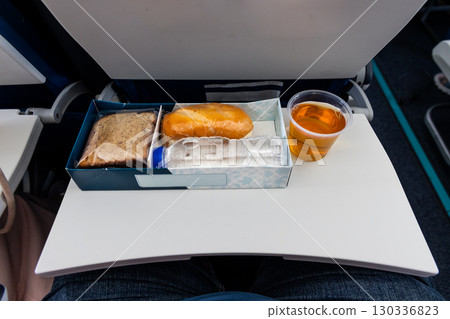 Simple mealbox with light snack, apple juice and water served in short haul flight 130336823