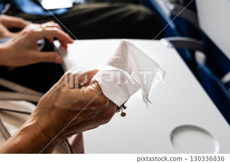 Air travel passenger preparing anti-bacterial wet wipes to sanitize personal space in air plane 130336836