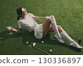 Stylish golfer woman with cocktail relaxing on course grass 130336897