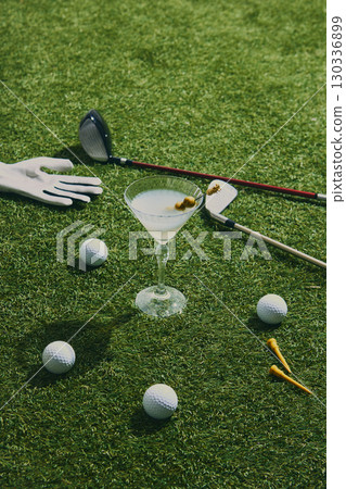 Golf cocktail with clubs glove balls and tees on course grass 130336899