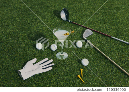 Golf martini cocktail with clubs balls and glove on green grass Golf martini cocktail with clubs balls and glove on green grass 130336900