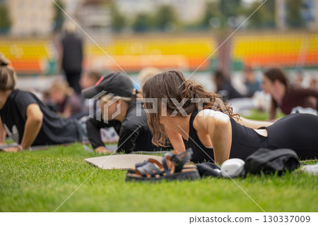 A young woman practicing FYSM yoga on a green stadium lawn A young woman practicing FYSM yoga on a green stadium lawn 130337009