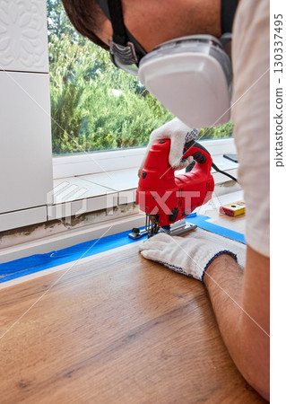 repairman using electric jigsaw and cutting hole for the sink in the kitchen countertops 130337495