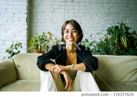A woman is sitting on a couch with a smile on her face A woman is sitting on a couch with a smile on her face 130337626