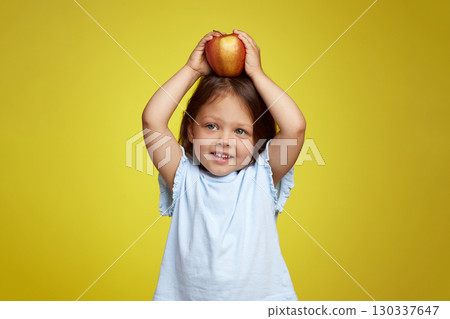 cute Caucasian little child girl holding apple on yellow background cute Caucasian little child girl holding apple on yellow background 130337647