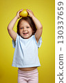 funny Caucasian little child girl holding lemon on yellow background 130337659