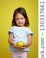 cute Caucasian little child girl holding lemon on yellow background 130337661