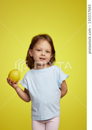 cute Caucasian little child girl holding lemon on yellow background cute Caucasian little child girl holding lemon on yellow background 130337665